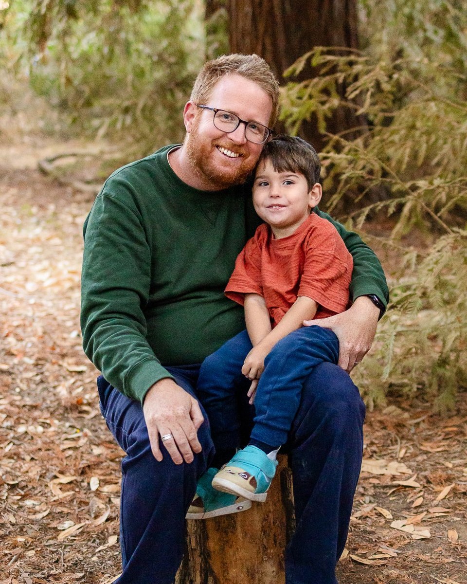 Thomas Wagner with his son Max on his lap among redwood trees, both smiling